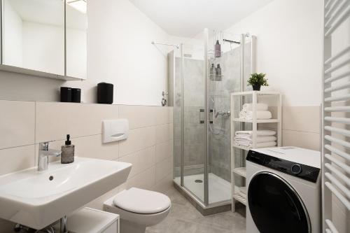 ein weißes Bad mit einem WC, einem Waschbecken und einer Dusche in der Unterkunft Aparte - Washer & Dryer - Kitchen & Parking - Smart-TV in Sarstedt