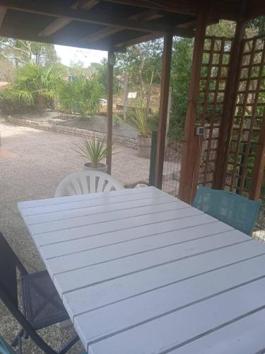 une table blanche et des chaises sur une terrasse dans l'établissement Maison au dessus du lac de Biscarrosse, à Biscarrosse