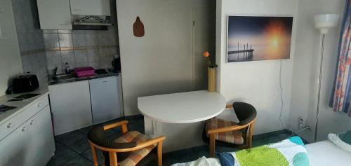 uma pequena cozinha com uma mesa branca e duas cadeiras em Miniferienhaus Bad Elster em Bad Elster