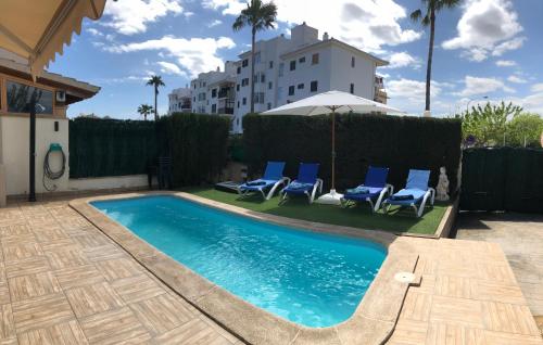 a swimming pool with blue chairs and a building at Casa Paraiso de Alcudia in Port d'Alcudia