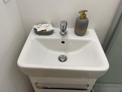 a white bathroom sink with a soap dispenser on it at Studio fonctionnel, pratique et bien placé in Vichy