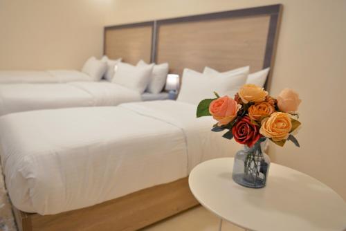 a bedroom with two beds and a vase with flowers on a table at Beit Alshabaan Inn in Wadi Musa