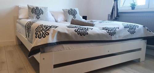 a bed with a white and black comforter and pillows at Apartamenty u Krysi 2 in Ząb