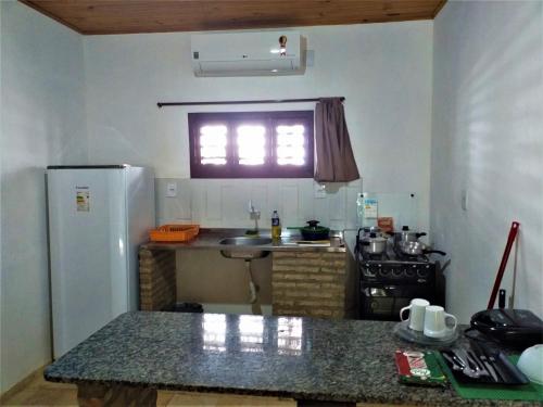 a kitchen with a refrigerator and a counter top at Chalés Hibiscus Pipa - ar, cozinha e banheiros privados, estacionamento interno in Pipa