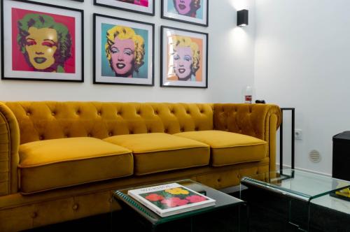 uma sala de estar com um sofá amarelo e algumas fotografias em Apartamentos Élite - Art Collection - Andy em Mérida