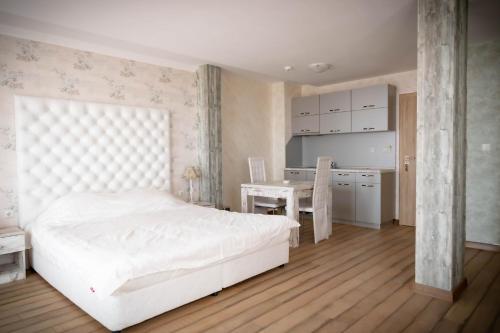 1 dormitorio con cama blanca y escritorio en семеен хотел Прованс Ахелой en Aheloy