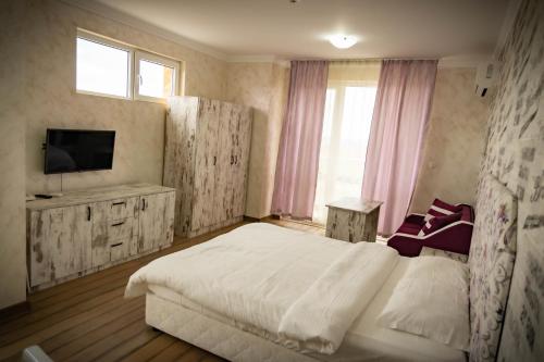 a bedroom with a white bed and a television at семеен хотел Прованс Ахелой in Aheloy