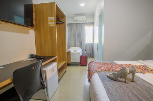 a hotel room with a bed with a pair of shoes on the bed at Hotel Horto in Rondonópolis