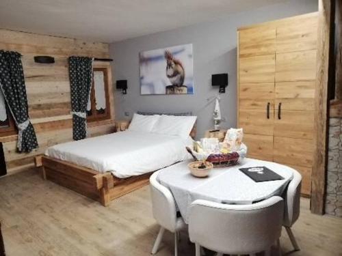 1 dormitorio con 1 cama y 1 mesa con sillas en FIOCCO DI NEVE, en Vezza d'Oglio
