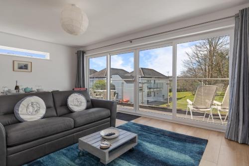 a living room with a couch and a large window at Coedrath Park 20 - Modern Apartment, Close to the Beach in Saundersfoot