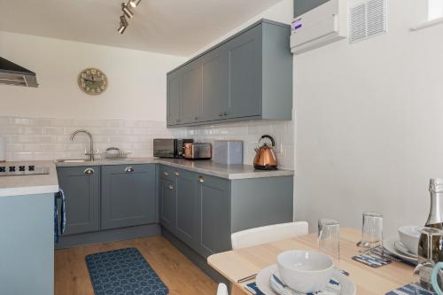 a kitchen with gray cabinets and a wooden table at Coedrath Park 20 - Modern Apartment, Close to the Beach in Saundersfoot