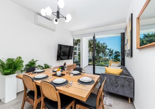a dining room with a table and chairs and a couch at Amazing &Totally New!!! Aria Ocean Condo 306 by Kivoya in Nuevo Vallarta