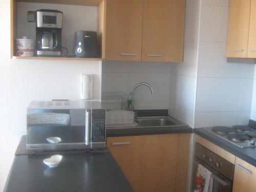 a kitchen with a microwave and a sink at Departamento Parque Urbano 1710 in Concepción