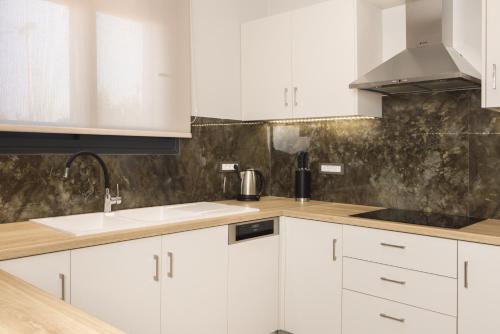 a white kitchen with white cabinets and a sink at Villa De Reve in Laganas