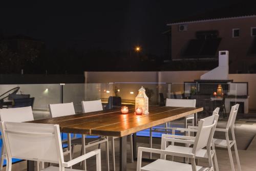 a wooden table and white chairs on a patio at Villa De Reve in Laganas