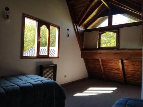 a bedroom with two windows and a bed in it at Habitacion privada en cabaña compartida "Los Cordobeses" in San Martín de los Andes