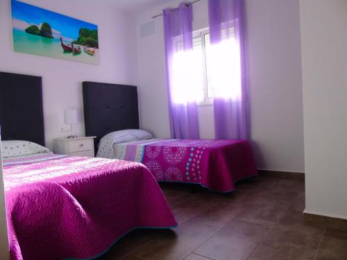 1 dormitorio con 2 camas con sábanas rosas y ventana en Casa rural Ajolí, en El Palmar