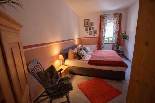 ein Schlafzimmer mit einem Bett, einem Stuhl und einem Fenster in der Unterkunft Ferienwohnung zur alten Post in Bad Grund