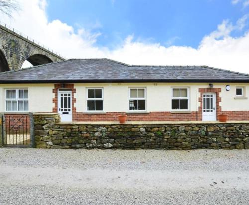 a brick and stone house with a stone wall at Holme Lea, Ingleton, North Yorkshire in Ingleton
