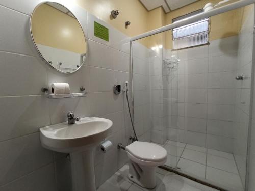 a bathroom with a toilet and a sink and a mirror at Lord Hotel Camburi in Vitória