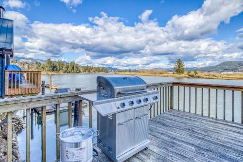 a grill on a deck next to a body of water at Coastal River Haven - Meredith Lodging in Nehalem