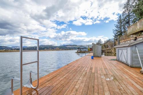 a dock on a lake with a building and the water at Coastal River Haven - Meredith Lodging in Nehalem
