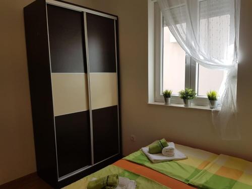 Schlafzimmer mit einem Bett und einem Fenster mit Pflanzen in der Unterkunft Apartments Hausmann in Novalja