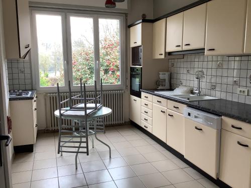 a kitchen with white cabinets and a table and chairs at Vos vacances dans le Morbihan in La Chapelle-Caro