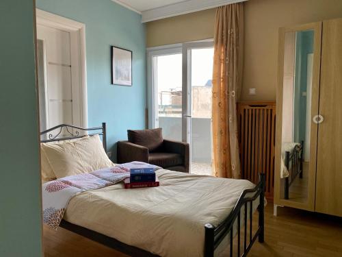 um quarto com uma cama, uma cadeira e uma janela em Einstein’s Apartment em Atenas