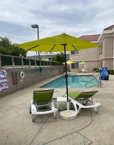 two chairs and an umbrella next to a pool at Comfort Suites in Tulare