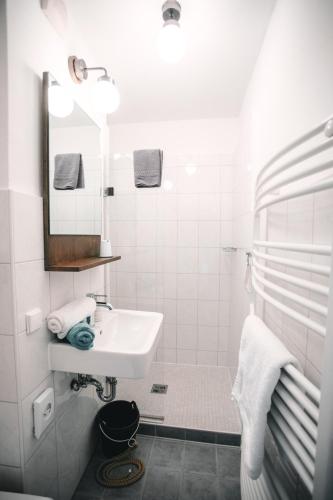 a white bathroom with a sink and a mirror at Pension Mai-Scholle in Borkum