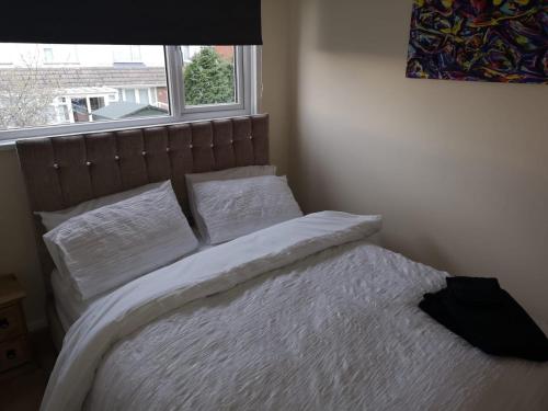 um quarto com uma cama com lençóis brancos e uma janela em Ffrith House em Prestatyn