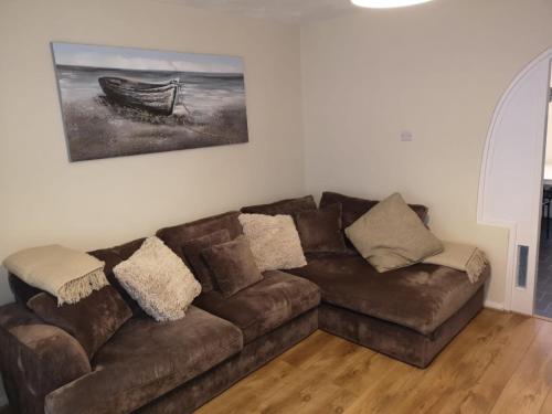 a brown couch in a living room with a painting on the wall at Ffrith House in Prestatyn