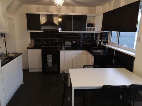 uma cozinha com armários brancos e uma mesa branca em Ffrith House em Prestatyn
