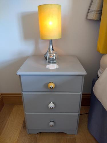 a nightstand with a lamp on top of it at Glenn Eireann House in Cushendun