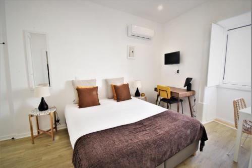 a bedroom with a large bed and a table and chairs at Sophia Studios in Coimbra