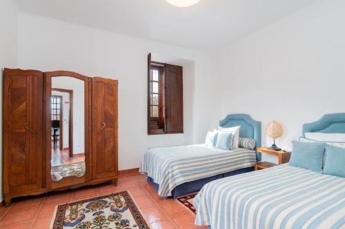 a bedroom with two beds and a dresser and a mirror at Casa do Boco in Oliveira do Hospital