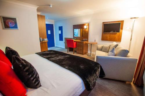 a hotel room with a large bed and a couch at Best Western Plus Lancashire Manor Hotel in Skelmersdale