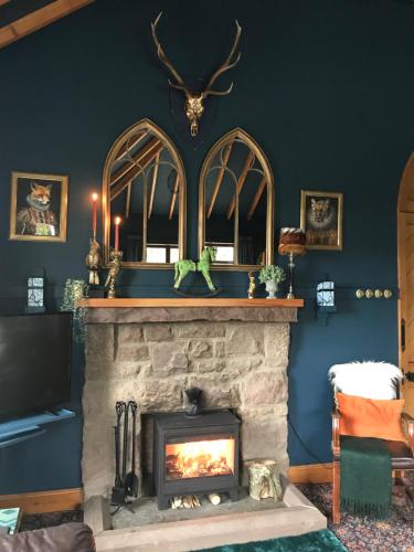 a fireplace in a living room with a blue wall at Cowden Farmhouse, near Stonehaven. in Glenbervie