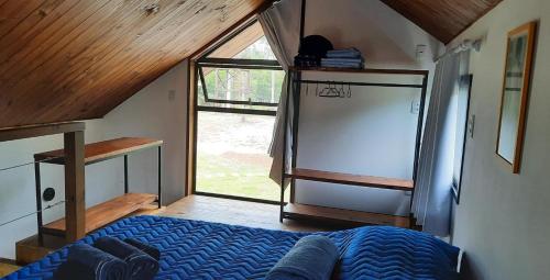 a bedroom with a bed and a large window at IbiraCottage in Imbituba