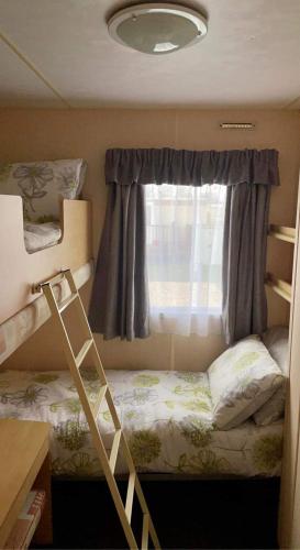 a small bedroom with a bunk bed and a window at dees caravan lettings kingfisher elm 453 in Ingoldmells