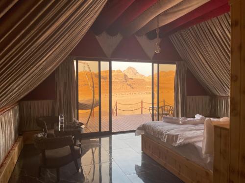 a bedroom with a bed and a table with a view at Rum Stars Camp in Wadi Rum