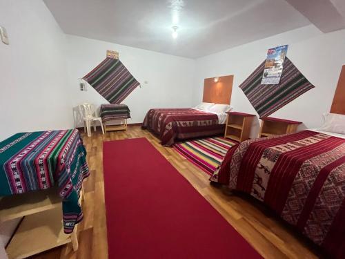 a room with two beds and a red carpet at Hotel Wiñay Pacha Inn in Puno