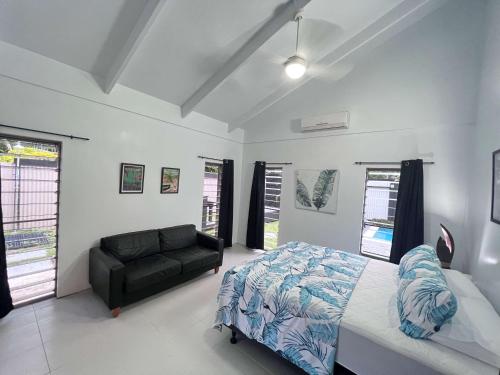 a bedroom with a bed and a couch at Sina Pool Villa Rarotonga in Arorangi