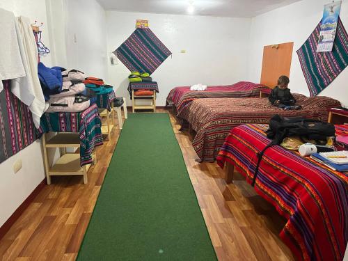 Habitación con 3 camas y alfombra verde. en Hotel Wiñay Pacha Inn, en Puno