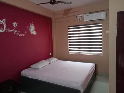 a bedroom with a white bed and a red wall at SAFA RESIDENCY in Perintalmanna