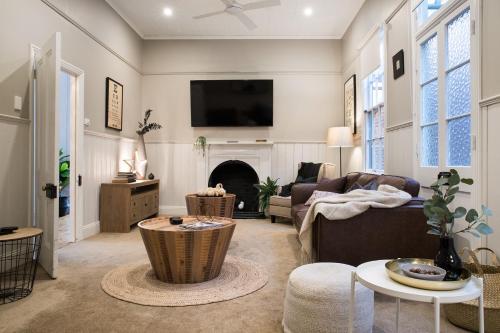 a living room with a couch and a tv at Albert Cottage - charming miner's cottage in town in Daylesford
