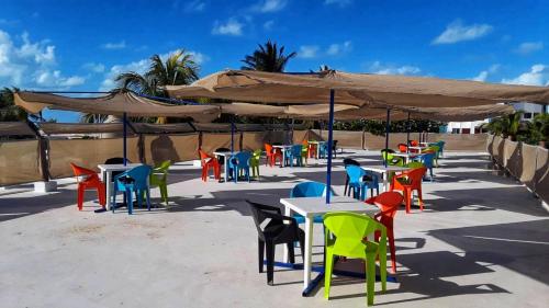 grupa stołów z kolorowymi krzesłami i parasolami w obiekcie Hotel Chuburna w mieście Chuburná