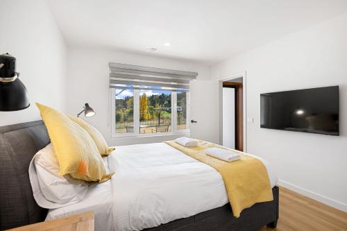 1 dormitorio con 1 cama con almohadas amarillas y TV en Lake Villavista, en Jindabyne