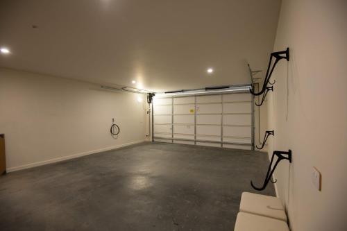 an empty garage with white garage doors and a couch at Lake Villavista - 4BR Luxury Townhouse l Pet Friendly l Lake Views l WiFi l BBQ in Jindabyne